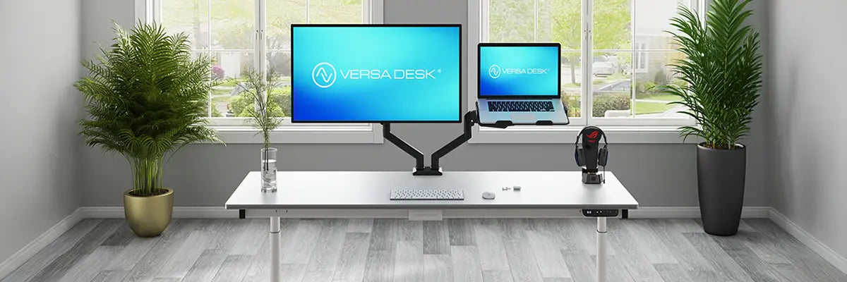 VersaDesk monitor arm holding a display and laptop mount side by side on a white desk with a gaming headset