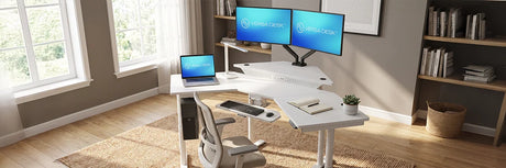 White VersaDesk L-shaped standing desk with dual monitors and laptop in bright home office with bookshelf, woven basket and natural window light